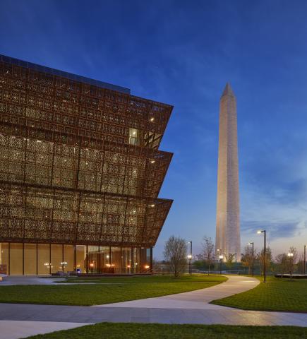African American Museum on left with Washington Monument on right, at dusk