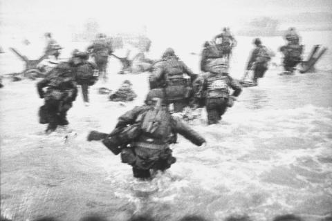 Soldiers wade through high water towards a beach