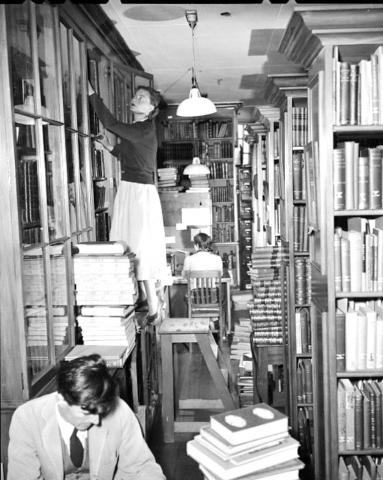 Library shelves and walkways full of books and readers
